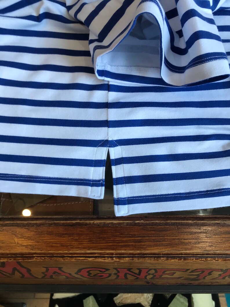 May include: A white and blue striped shirt with a side seam detail. The shirt is made of a soft, comfortable fabric.