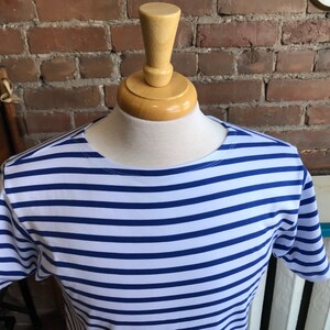 May include: A white and blue striped short-sleeved shirt with a round neckline.