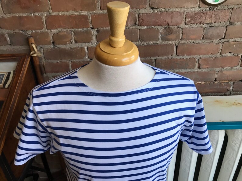 May include: A white and blue striped short-sleeved shirt with a round neckline.