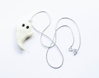 Può includere: Una collana con un ciondolo a forma di fantasma bianco con occhi neri su una catena d'argento.