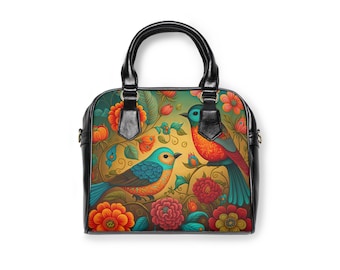 Könnte beinhalten: Eine schwarze Handtasche mit einem floralen und Vogel-Design. Die Tasche hat zwei Henkel und einen Reißverschluss. Das Blumenmuster zeigt rote, orange, gelbe, grüne und blaue Blumen. Die Vögel sind blau und orange.