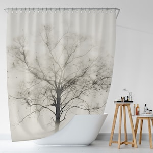 May include: A shower curtain with a black and white image of a bare tree with branches reaching towards the sky. The background is a light beige color.