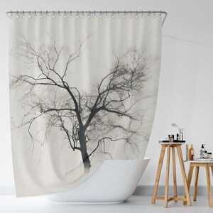 May include: A white shower curtain with a black and white silhouette of a bare tree printed on it. The shower curtain is hanging in a bathroom with a white bathtub and wooden stools.