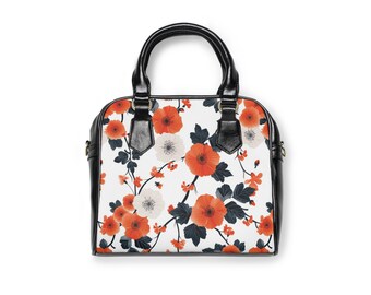 Könnte beinhalten: Eine schwarze Handtasche mit weißem Hintergrund und einem Blumendesign aus orangefarbenen und weißen Blüten. Die Handtasche hat zwei schwarze Henkel.