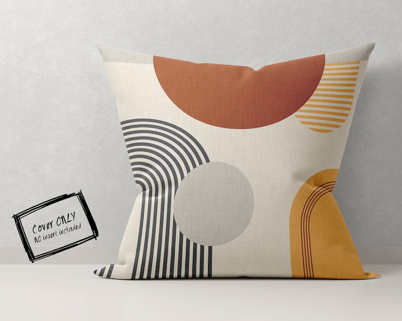 May include: A square decorative pillow cover with an abstract design. The pillow features geometric shapes in rust, mustard yellow, gray, and black on a cream background. The text "COVER ONLY NO insert included" is in the lower left corner.