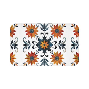 May include: A white bath mat with a repeating pattern of orange, yellow, and blue stylized flowers. The flowers have a dark blue center and are surrounded by dark blue leaves.