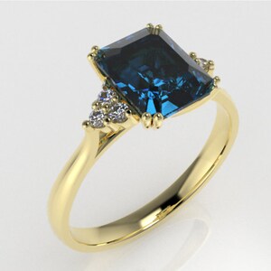 May include: A gold ring with a large, square-shaped blue gemstone surrounded by smaller, white gemstones. The ring is set in a simple, elegant style.