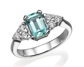 May include: A silver ring with a large, emerald-cut aquamarine gemstone surrounded by smaller diamonds.