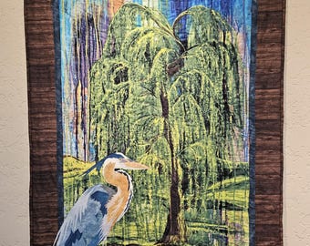 Tapiz de pared acolchado con motivos de la naturaleza: una garza azul bordada en la orilla de un arroyo con un sauce, ideal para los amantes de las aves.