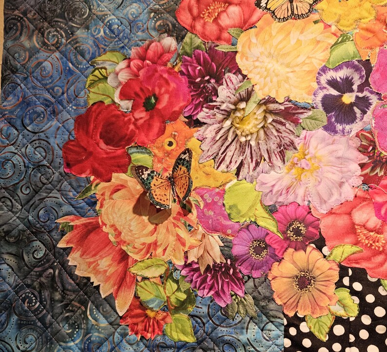 Puede incluir: Una tela floral colorida con una variedad de flores, incluyendo rojas, rosas, amarillas y moradas. La tela presenta una mariposa en el centro y un patr&oacute;n de lunares negros y blancos en el fondo.