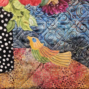 Puede incluir: Una colcha de retazos colorida con una aplicaci&oacute;n de p&aacute;jaro. El p&aacute;jaro es amarillo, verde y naranja con un ojo azul. La colcha est&aacute; hecha de varias telas con un patr&oacute;n de remolino azul y blanco, un patr&oacute;n de lunares negros y blancos y un patr&oacute;n floral marr&oacute;n y naranja.