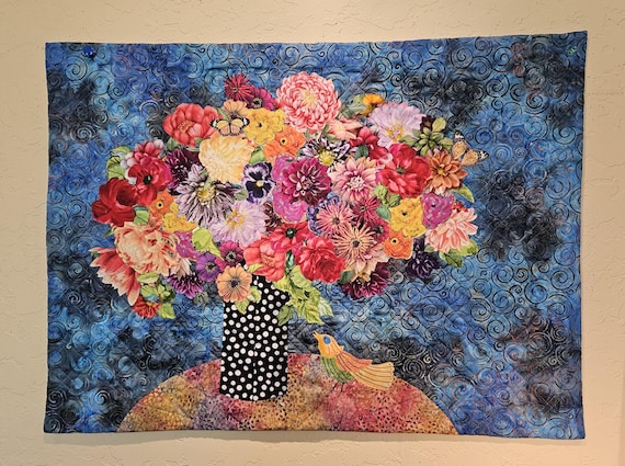 Quilted floral wall hanging- Still life of large appliqued flower bouquet with hand-embroidered yellow bird on finely quilted blue batik