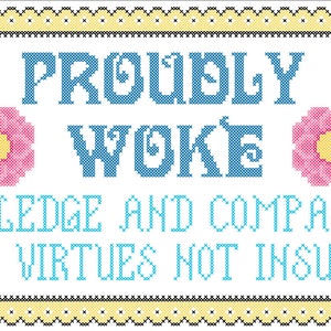 May include: A white cross-stitch embroidery with a yellow border and a blue and pink design. The text reads "Proudly Woke" and "Knowledge and Compassion are Virtues not Insults".