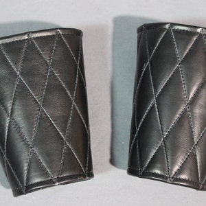 May include: A pair of black leather arm warmers with a diamond quilted pattern.