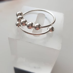 May include: A silver ring with a row of small silver beads on a double band.