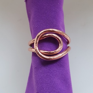 May include: A copper ring with a hammered finish and a double-loop design.