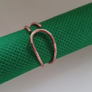 May include: A rose gold ring with a hammered finish. The ring is made of two bands that are intertwined.