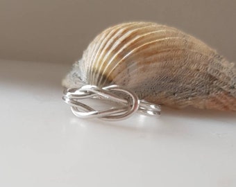 Op de afbeelding: Een zilveren knoop ring met een eenvoudig ontwerp. De ring is gemaakt van gedraaid draad en heeft een gladde afwerking.