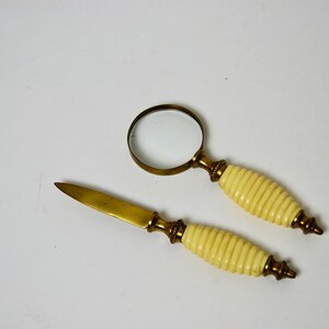 May include: A set of two brass desk accessories with ivory handles. The set includes a magnifying glass and a letter opener.