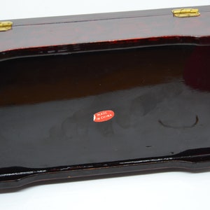 Peut inclure: Une bo&icirc;te rectangulaire en bois laqu&eacute; avec une finition brillante brun-rouge fonc&eacute;. La bo&icirc;te a un couvercle &agrave; charni&egrave;re avec une quincaillerie de couleur laiton. Un autocollant rouge avec le texte blanc "MADE IN CHINA" est appos&eacute; au fond.
