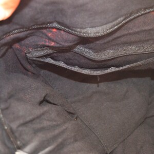 May include: The inside of a black fabric bag with a zippered pocket. The bag is lined with black fabric.