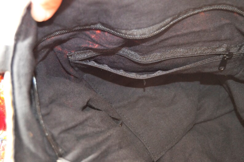 May include: The inside of a black fabric bag with a zippered pocket. The bag is lined with black fabric.