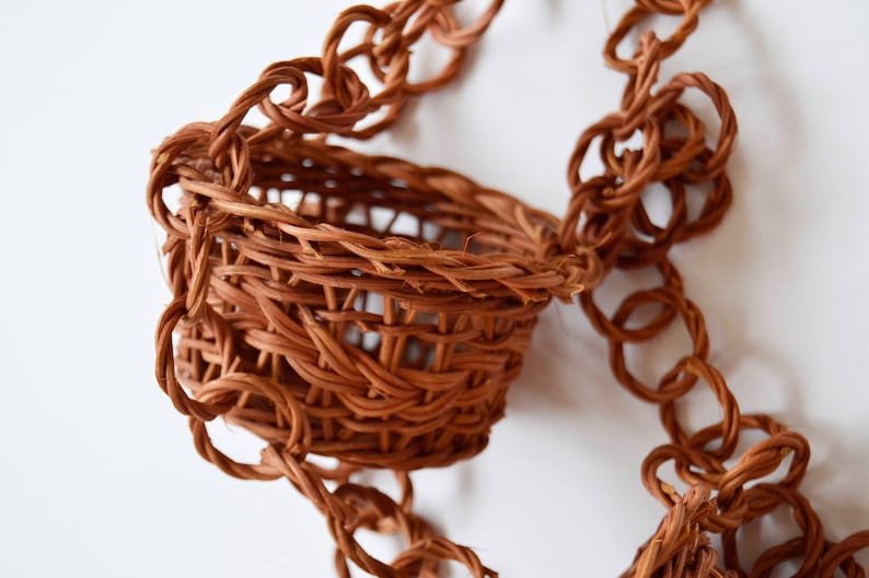 May include: A brown woven hanging basket with a braided rope handle.