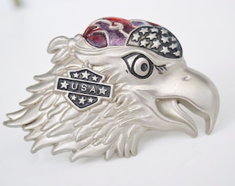 May include: Silver eagle belt buckle with a red, white and blue bandana and a shield with the word "USA" and stars.
