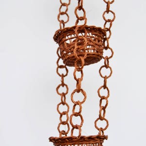 May include: Three brown wicker hanging baskets with a woven chain.