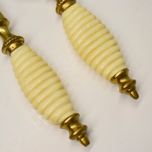 May include: A pair of brass letter openers with ivory-colored handles. The handles have a spiral design.