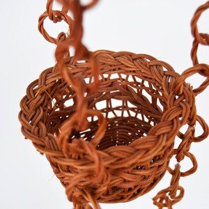 May include: A brown wicker hanging basket with a woven chain.