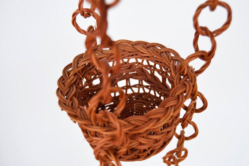 May include: A brown wicker hanging basket with a woven chain.