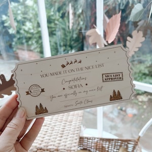 May include: A rectangular wooden ticket with scalloped edges featuring laser-engraved text that reads: YOU MADE IT ON THE NICE LIST, Congratulations SOFIA, You are officially on my nice list, Signed by: Santa Claus, and NICE LIST APPROVED.
