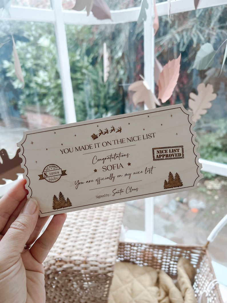 May include: A rectangular wooden ticket with scalloped edges featuring laser-engraved text that reads: YOU MADE IT ON THE NICE LIST, Congratulations SOFIA, You are officially on my nice list, Signed by: Santa Claus, and NICE LIST APPROVED.