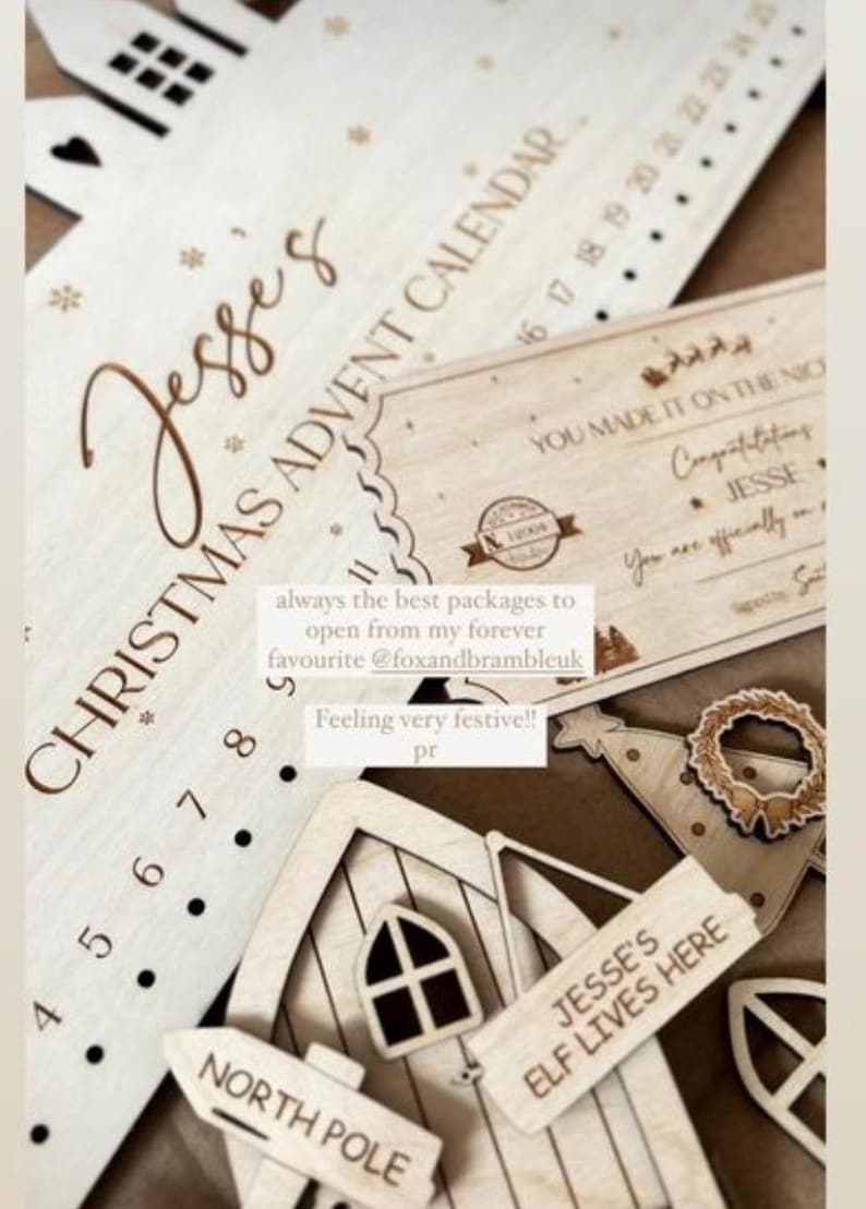 May include: A light-colored wooden Christmas advent calendar with the text Jesse's Christmas Advent Calendar, a rectangular certificate with the text You Made It On The Nice List, and a small wooden house sign labeled Jesse's Elf Lives Here.
