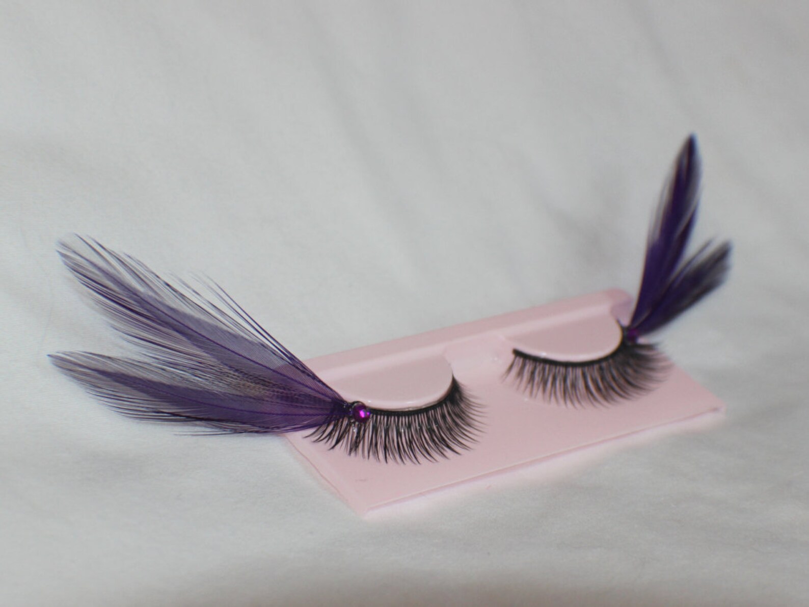 Purple feather false eyelashes with rhinestone details, perfect for dramatic gothic lashes and creative goth eye makeup.