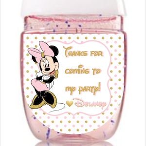 May include: Pink and gold Minnie Mouse party favor hand sanitizer bottle with a white label that says "Thanks for coming to my party! Delaney".