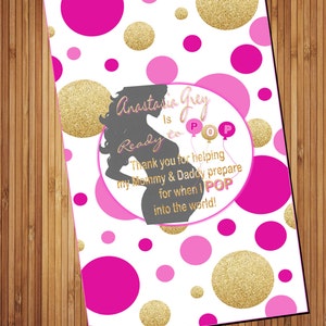 May include: Pink and gold polka dot baby shower favor tag with the text "Anastasia Grey is Ready to POP" and a silhouette of a pregnant woman.