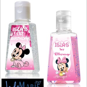 May include: Two clear plastic bottles of hand sanitizer with pink and white labels featuring a cartoon image of Minnie Mouse. The labels also include the text "Isla's 1st Birthday".