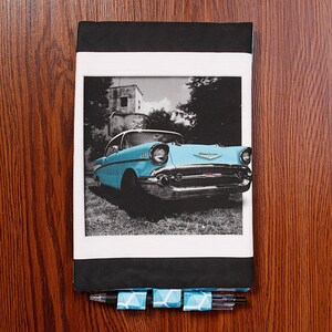 May include: A blue 1957 Chevrolet Bel Air classic car in a black and white photo on a notebook cover with a blue and white patterned pen.