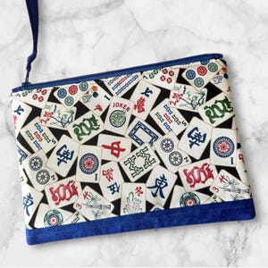 May include: A white ceramic mug with a black handle and the text "But First, Coffee" in a bold, black font. The mug is set against a blurred background, suggesting a cozy setting.