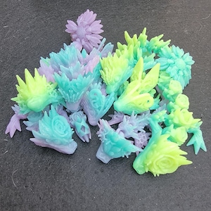 Pu&ograve; includere: Una collezione di figurine in resina stampate in 3D in varie tonalit&agrave; di verde, blu e viola. Le figurine sono dettagliate e intricate, con una variet&agrave; di forme e design.