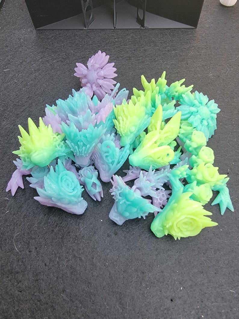 Pu&ograve; includere: Una collezione di figurine in resina stampate in 3D in varie tonalit&agrave; di verde, blu e viola. Le figurine sono dettagliate e intricate, con una variet&agrave; di forme e design.