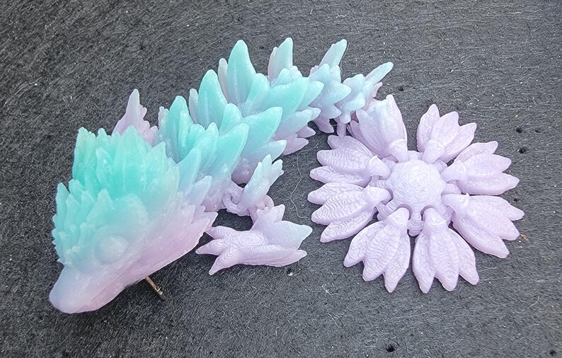 Pu&ograve; includere: Un paio di sculture decorative in cristallo color pastello. Una scultura &egrave; una figura di drago con un gradiente dal rosa al blu. L'altra scultura &egrave; una forma di fiore di colore viola.
