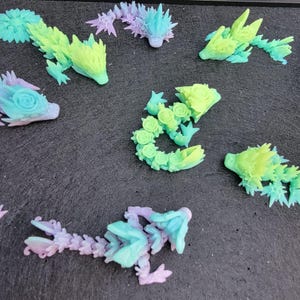 Pu&ograve; includere: Una collezione di sette piccole figurine di creature fantastiche stampate in 3D e colorate. Le figurine sono realizzate in plastica trasparente e presentano una variet&agrave; di colori, tra cui verde, blu, viola e rosa.
