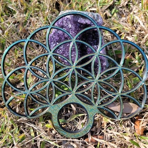 May include: A green and black wooden mandala with a geometric design. The mandala is made of overlapping circles and has a glittery finish.