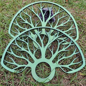 May include: Two semi-circular green wooden cutouts featuring an intricate, branching tree-like pattern. Each piece has a circular opening at the base and thin, radiating lines that resemble bare tree limbs extending toward the curved outer edge.