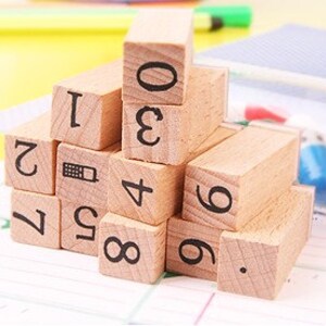 May include: Wooden blocks with numbers 0 through 9 and a phone icon printed on them. The blocks are stacked in a pyramid shape.