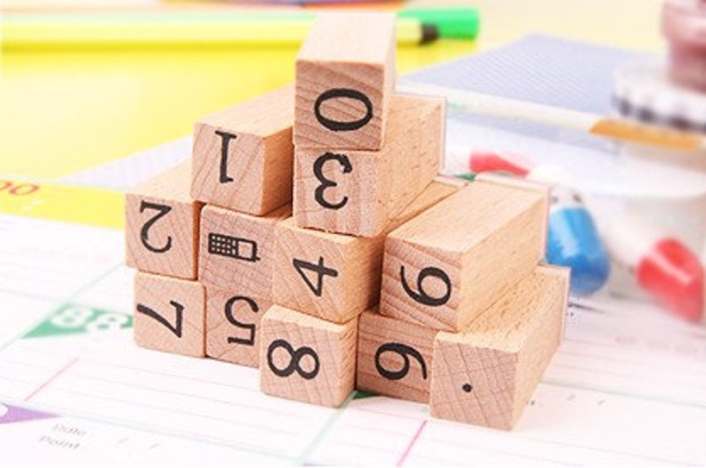 May include: Wooden blocks with numbers 0 through 9 and a phone icon printed on them. The blocks are stacked in a pyramid shape.