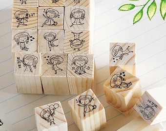 Puede incluir: Un conjunto de 16 sellos de madera con ilustraciones de niñas en varias poses. Los sellos son cuadrados y tienen un acabado de madera natural. Las ilustraciones son en blanco y negro e incluyen detalles como corazones, estrellas y notas musicales.